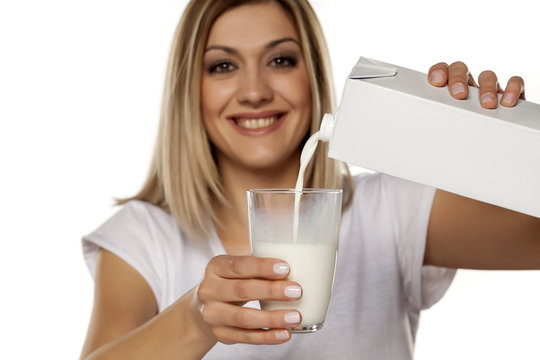 smiling young woman pours milk in a glass