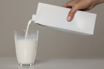 pouring milk from the carton into a glass