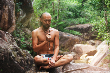 Yogi is sitting on the stone in jungle