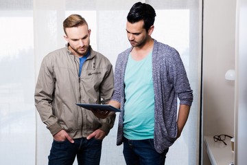 Focused gay couple looking at tablet - Powered by Adobe