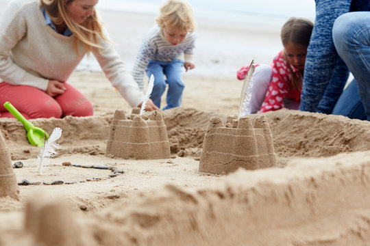 Family Building Sandcastles On Beach Together