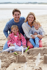 Fototapeta premium Portrait Of Family Building Sandcastles On Beach Together