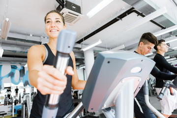 Fototapeta premium Young fit woman using an elliptic trainer