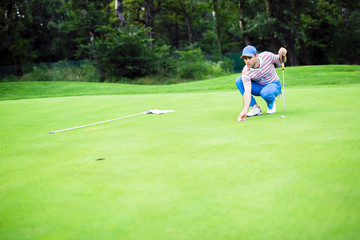 Obraz premium Golf player marking ball on the putting green