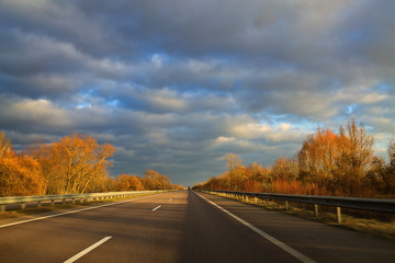 Highway autumn cloudy day with trees on the roadside