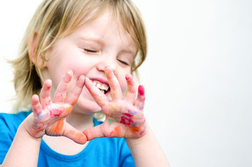 Cute preschooler girl with smile showing colored hands. Selectiv