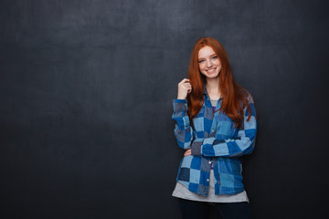 Happy woman with red hair standing over blackboard background
