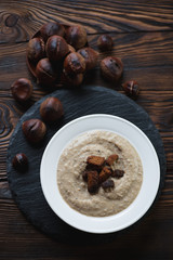 Above view of chestnut cream-soup served with croutons, close-up