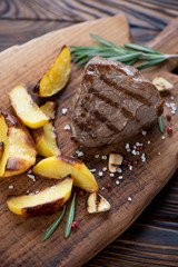Closeup of grilled filet mignon steak with roasted potato slices