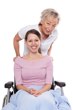 Junge Frau im Rollstuhl mit älterer Krankenpflgerin, Freigestel
