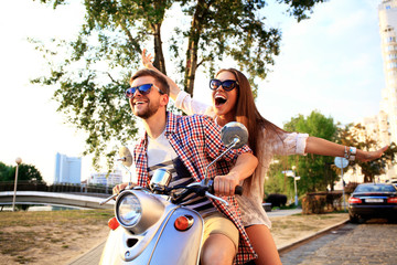Portrait of happy young couple on scooter enjoying road trip