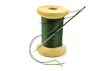 Wooden coil with threads and a needle for sewing on a white background