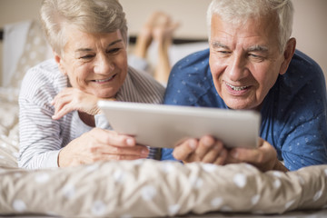 Grandparents resting while using a digital tablet