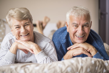 Senior couple in pajamas on the bed.