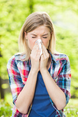 Woman with allergy symptom blowing nose 