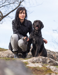 Beautiful girl with mutt black dog on mountains
