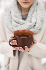 female hands holding a mug of hot tea