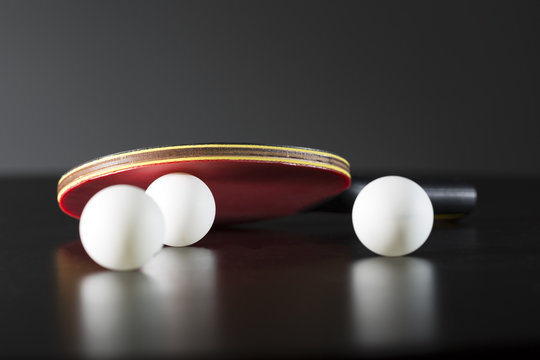 table tennis racket and balls on dark table