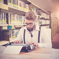 Composite image of hipster smoking pipe working on typewriter