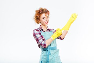 Happy housewife in blue apron wearing yellow gloves