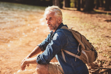 Senior male hiker sitting next to a lake
