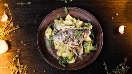 Fried fish with potato and vegetables on a wooden background top view
