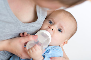 Obraz na płótnie Canvas mother feeding her baby infant from bottle