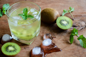 Cocktail with kiwi and mint in a glass on a wooden background