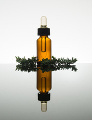 thyme leaves with essential oil amber glass bottle with dropper, vertical with reflection - 102823607