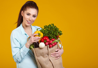 beautiful young woman with fruits and vegetables in shopping bag