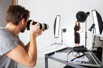 Photographer shooting model in studio - obrazy, fototapety, plakaty