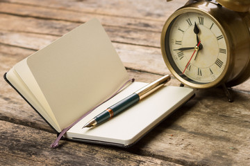 Open notebook with fountain pen and alarm clock