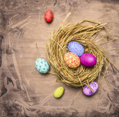 painted eggs for Easter nest on wooden rustic background top view close up