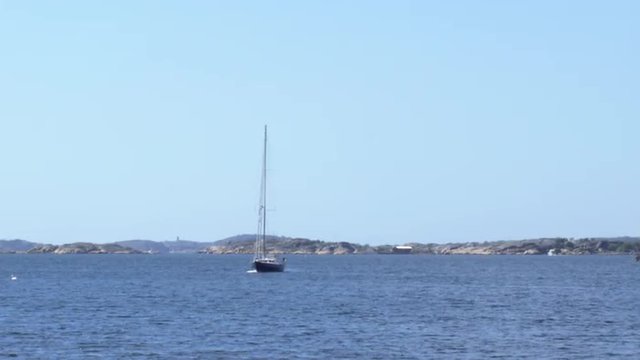 A sailboat is on the ocean by rocky islands a beautiful day at the end of May in the Gothenburg archipelago, Sweden.
