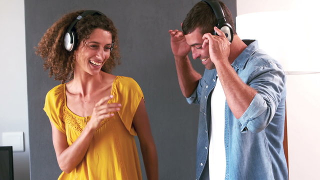 Cute couple listening to music with headphones and dancing