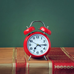 Red alarm clock on the table with a red tablecloth.