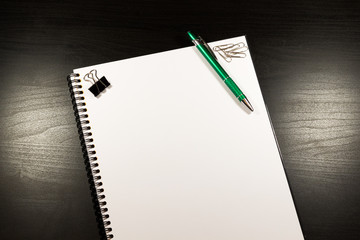 Notebook with blank paper, color sticky notes, pen and clips on a wooden table