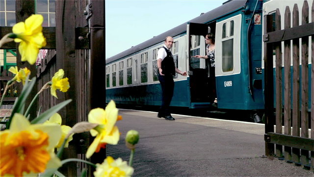 British Railway: station master helping passenger alight from train