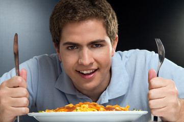 Portrait of a young man eating spaghetti