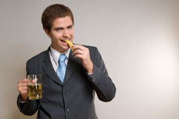Business man holding a chop of beer and eating french fries