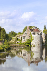 Fototapeta na wymiar 14th century moated English medieval castle Scotney in Kent countryside surrounded by romantic gardens, woodlands, with ruined castle reflected in the lake with floating water white lilies
