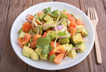Fresh avocado Salad  with tomatoes, purple onion on the white dish. Healthyt food concept
