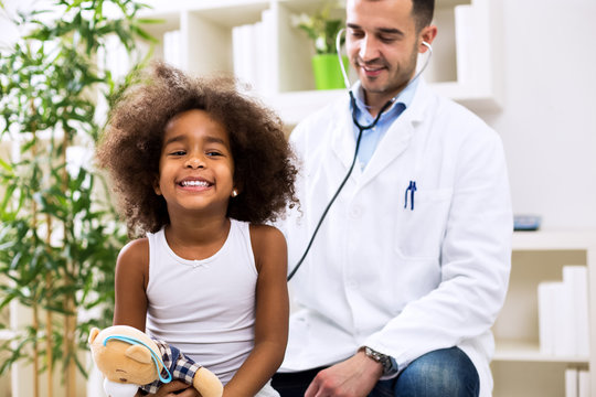 Doctor pediatrician examining cute smiling african girl