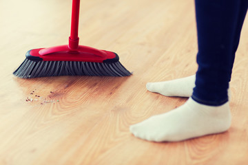 close up of woman legs with broom sweeping floor