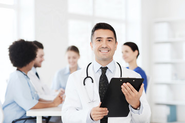happy doctor with clipboard over medical team