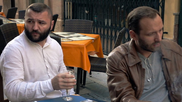 Two offended friends sitting with beer and cigarettes in cafe, super slow motion

