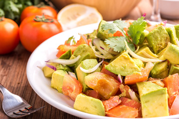 Fresh avocado Salad  with tomatoes, purple onion on the white dish. Healthyt food concept