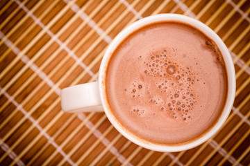 Cup of cocoa with milk on bamboo napkin