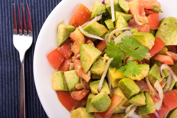 Fresh avocado Salad  with tomatoes, purple onion on the white dish. Healthyt food concept