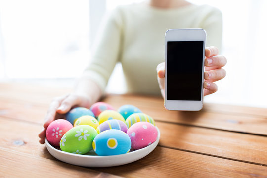 close up of hands with easter eggs and smartphone